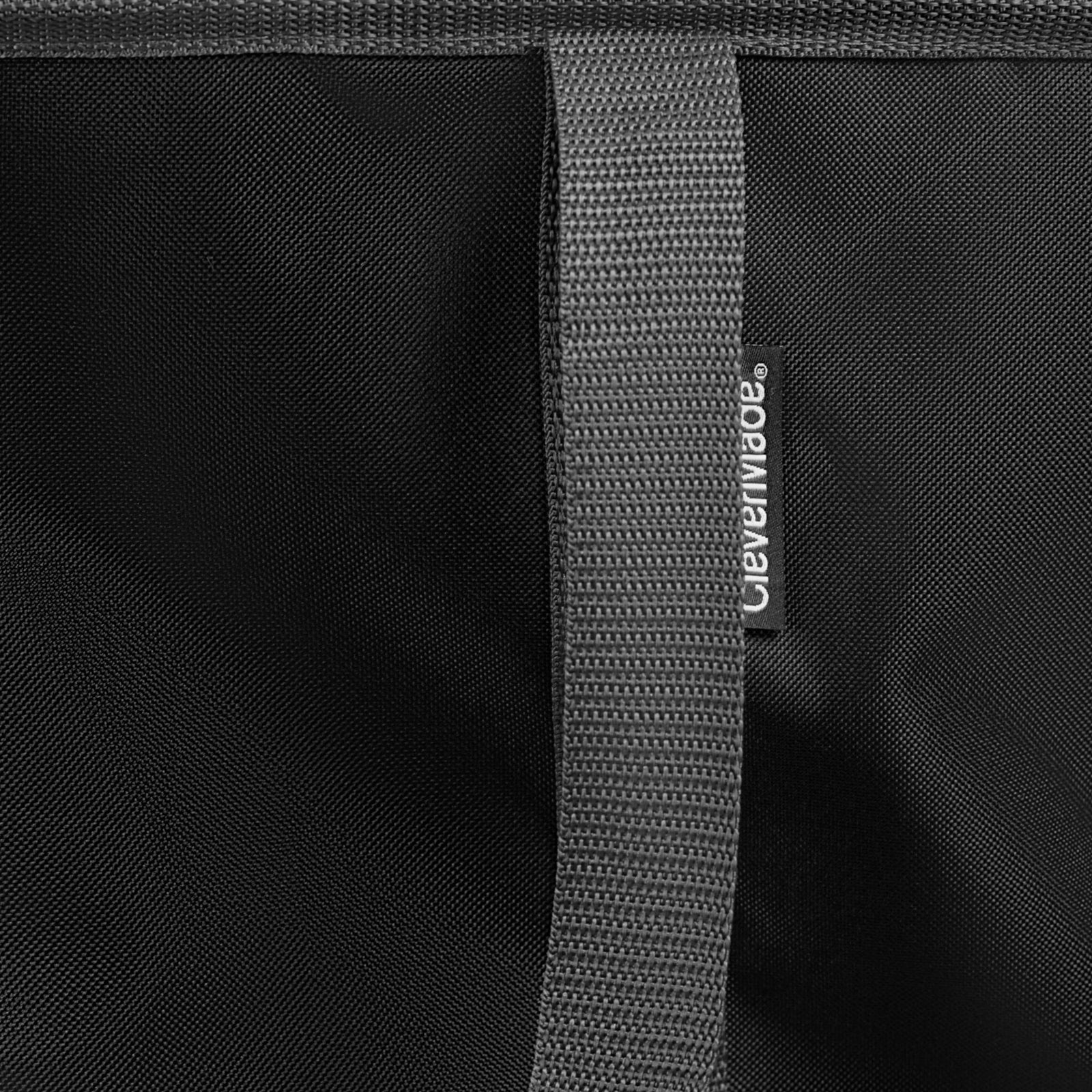 Close-up of a black bag with a gray strap featuring a brand logo.