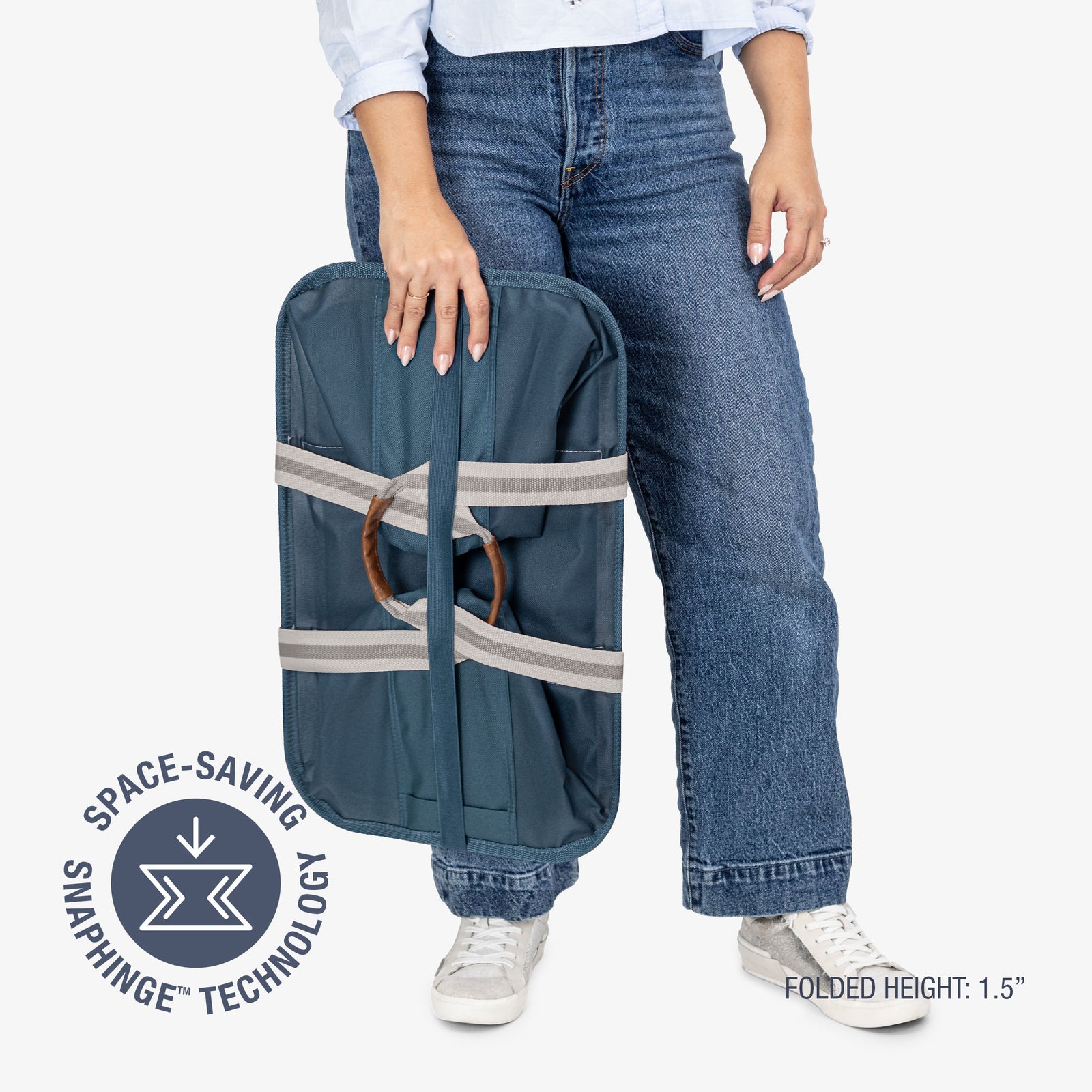 Person holding a blue laundry tote bag with space-saving snap hinge technology on a white background