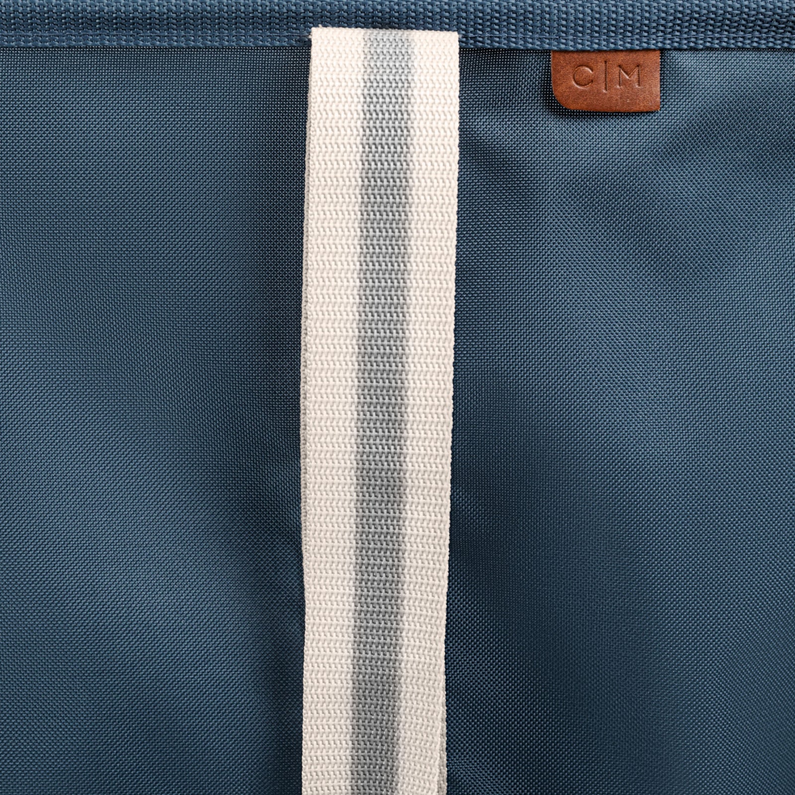 Close-up of a blue bag with a white strap and a brand logo.