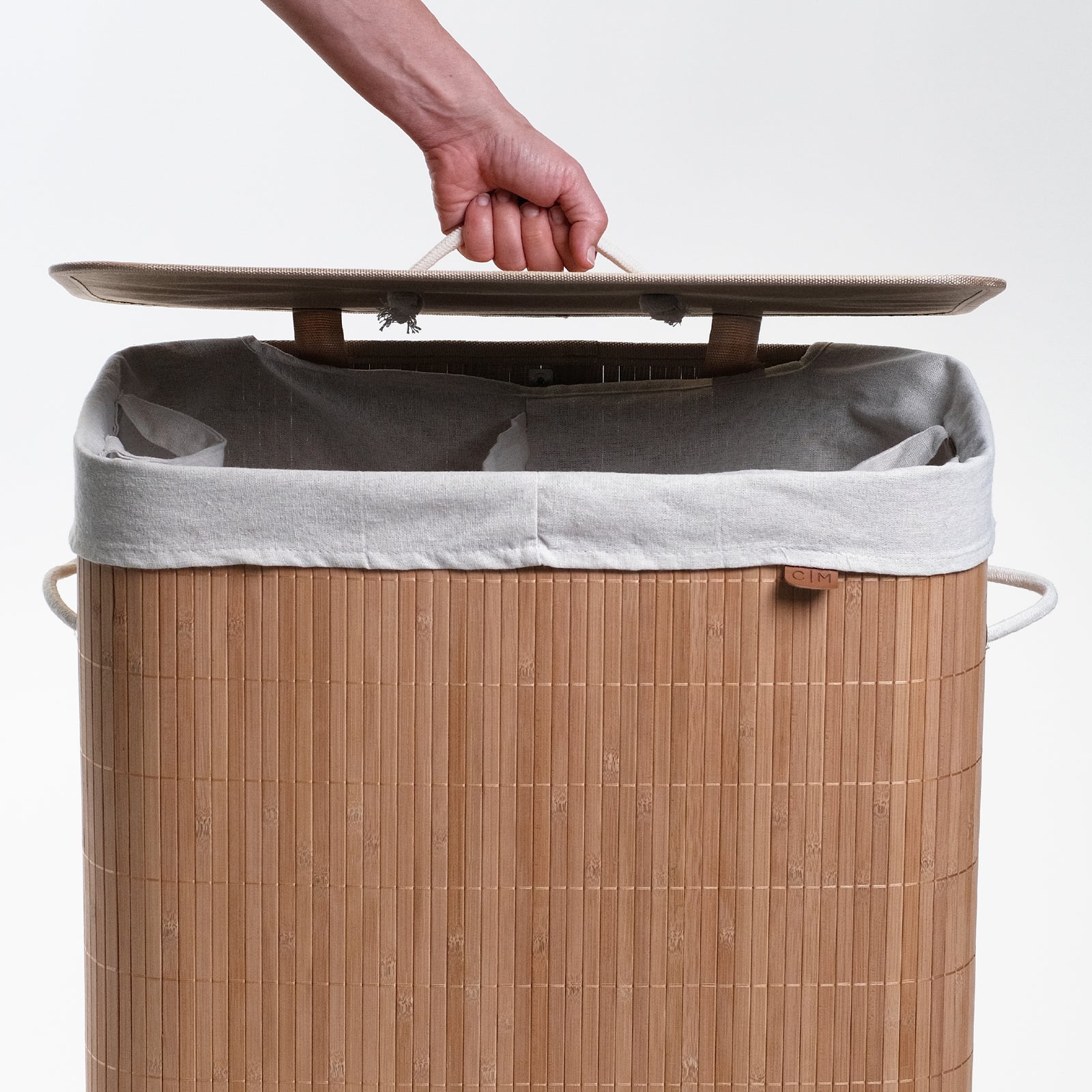 Opening cover of collapsible bamboo laundry hamper with a lid and handles, featuring a natural beige color.