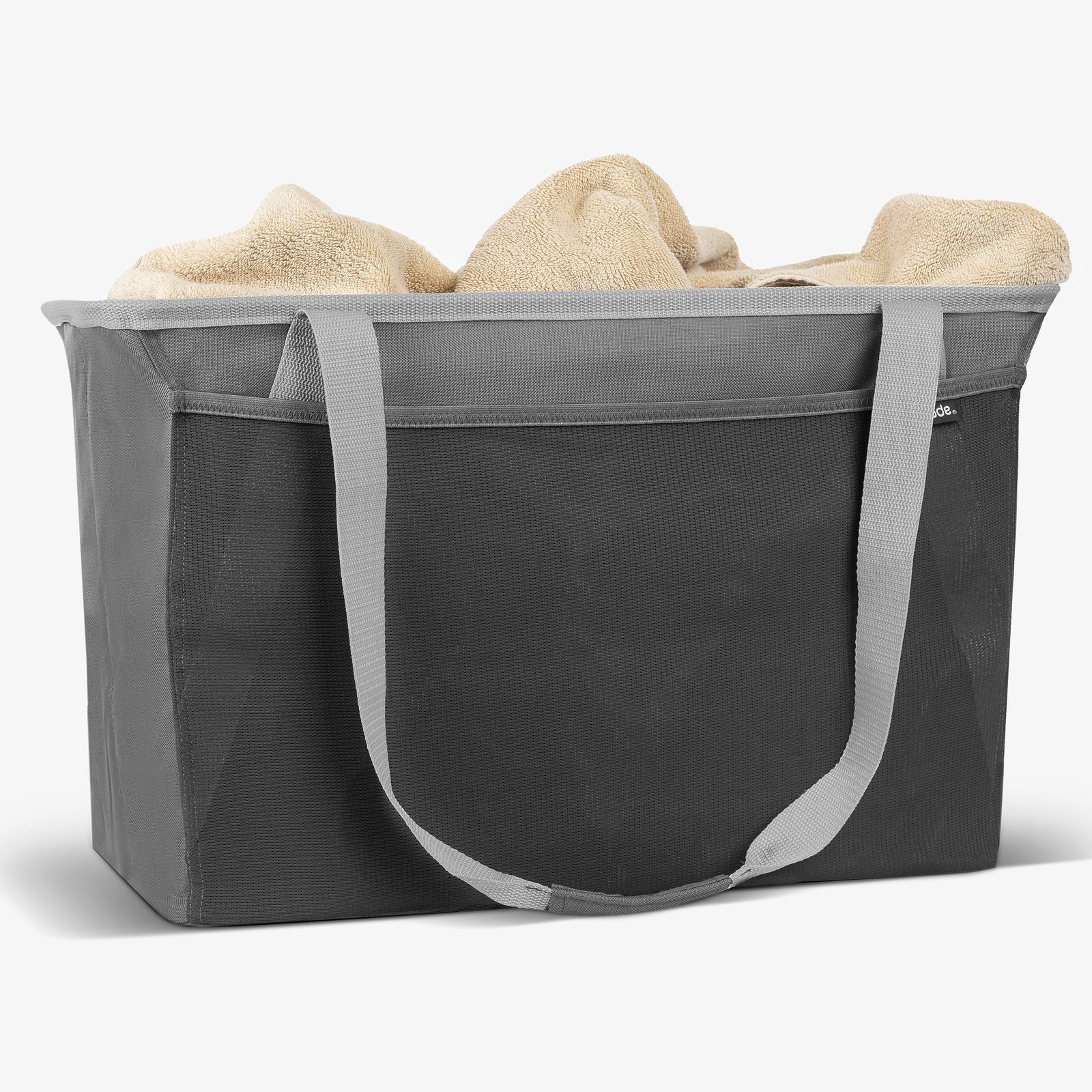 Gray collapsible tote with handles filled with beige towels on a white background
