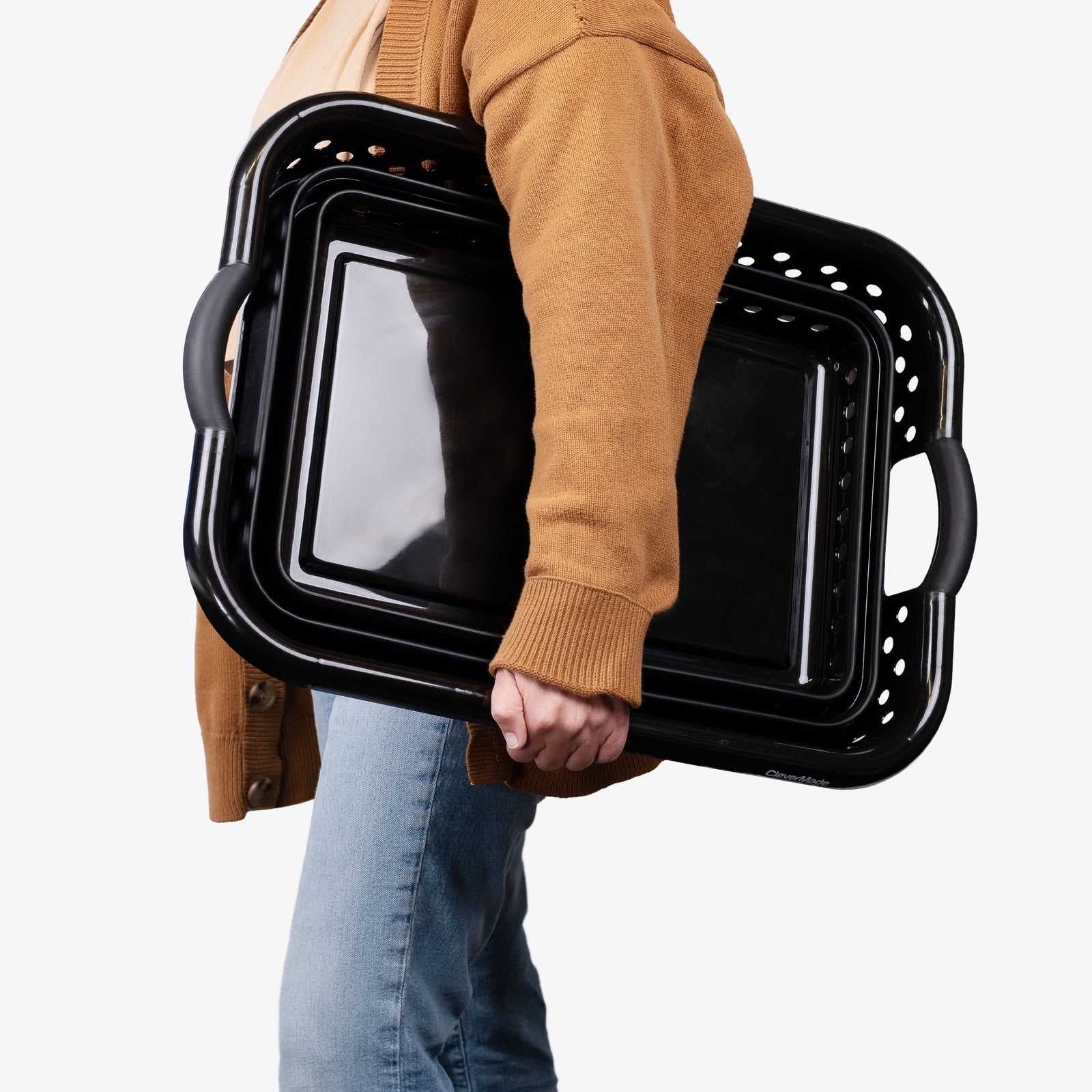 Person holding folded collapsible plastic laundry basket with handles on a white background