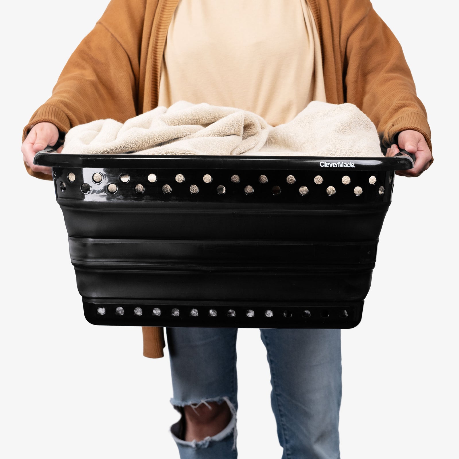 Person holding a black Collapsible Laundry Basket with clothes inside on a white background