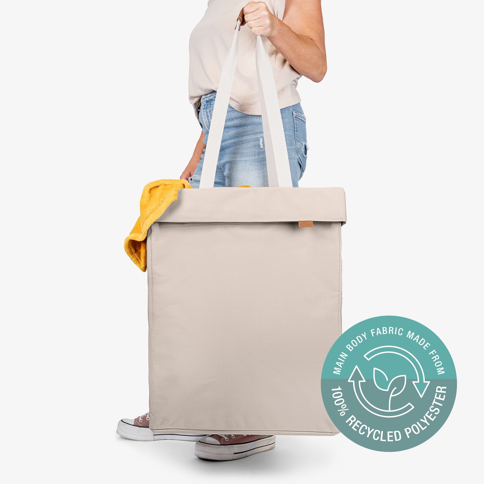 Cream tote bag with recycled polyester label held by a person on a white background