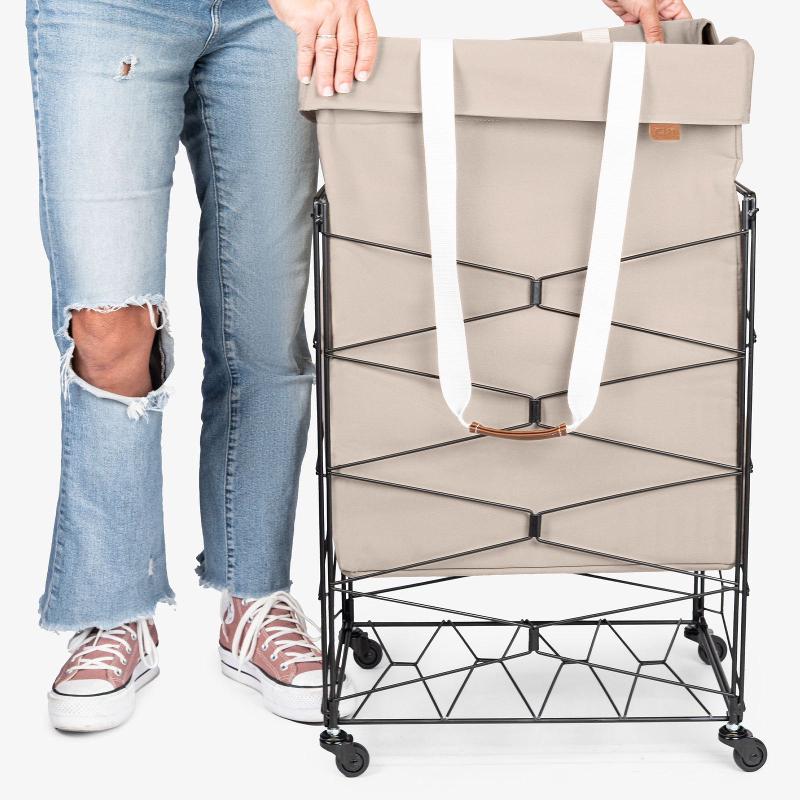 Person holding a cream laundry basket with wheels on a white background