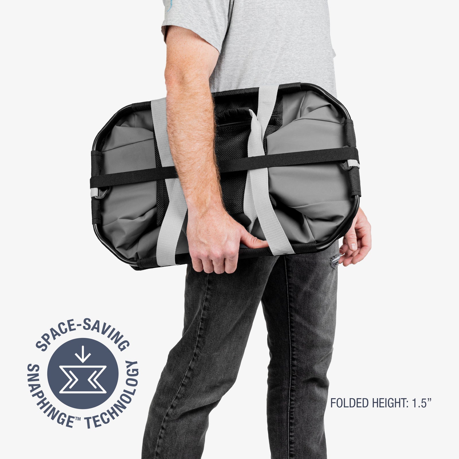 Person holding a gray duffel bag with space-saving snap hinge technology on a white background