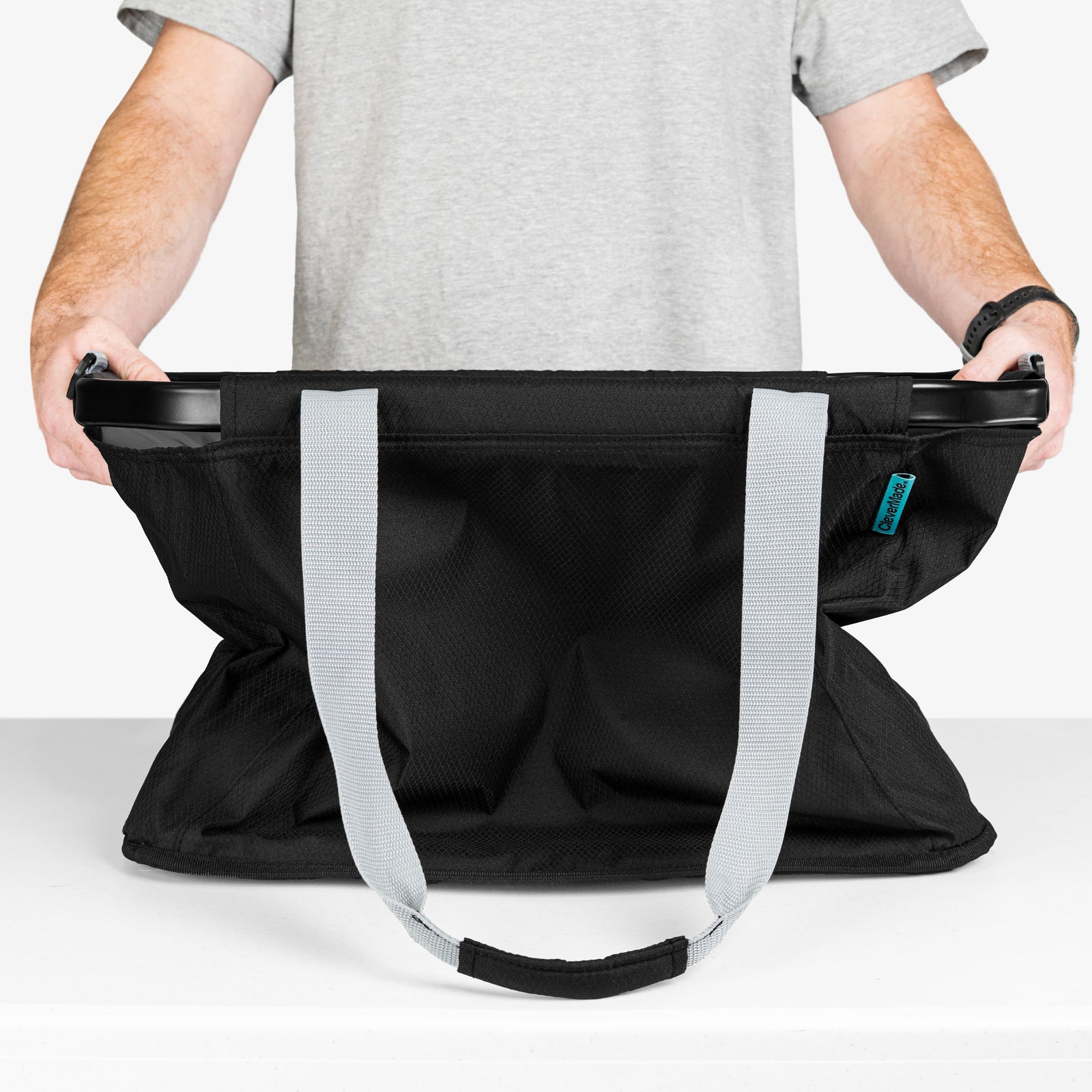 Person holding a black bag with gray straps on a white background