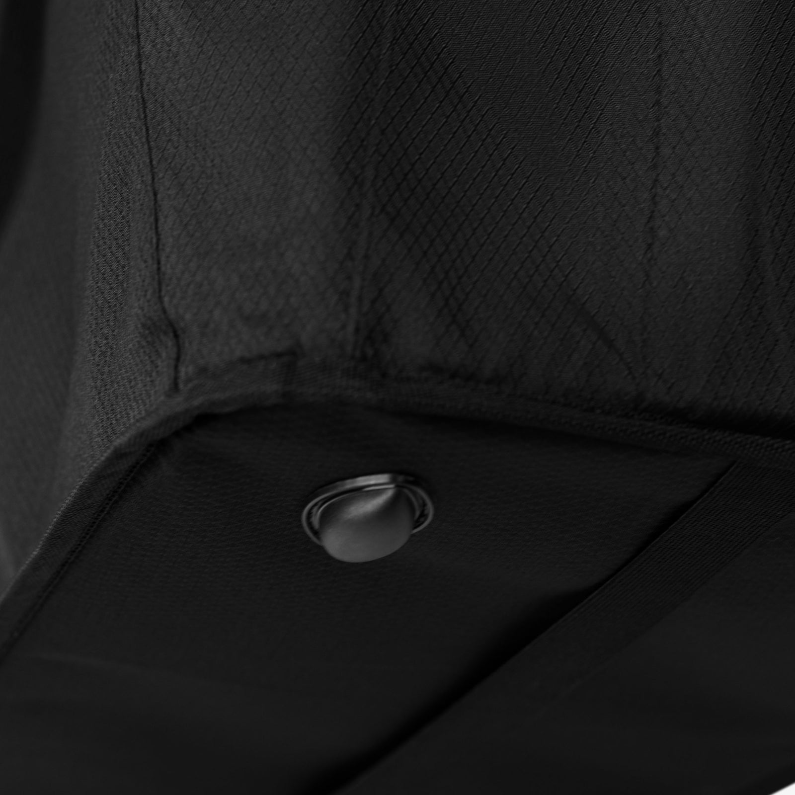 Close-up of a black textured surface with a metallic button.