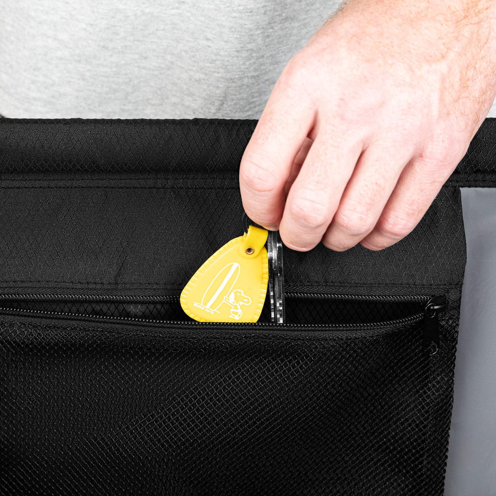 Person using a yellow tool to open a black bag
