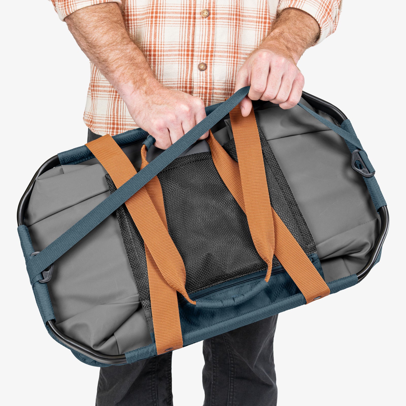 Person holding a gray duffel bag with brown straps on a white background