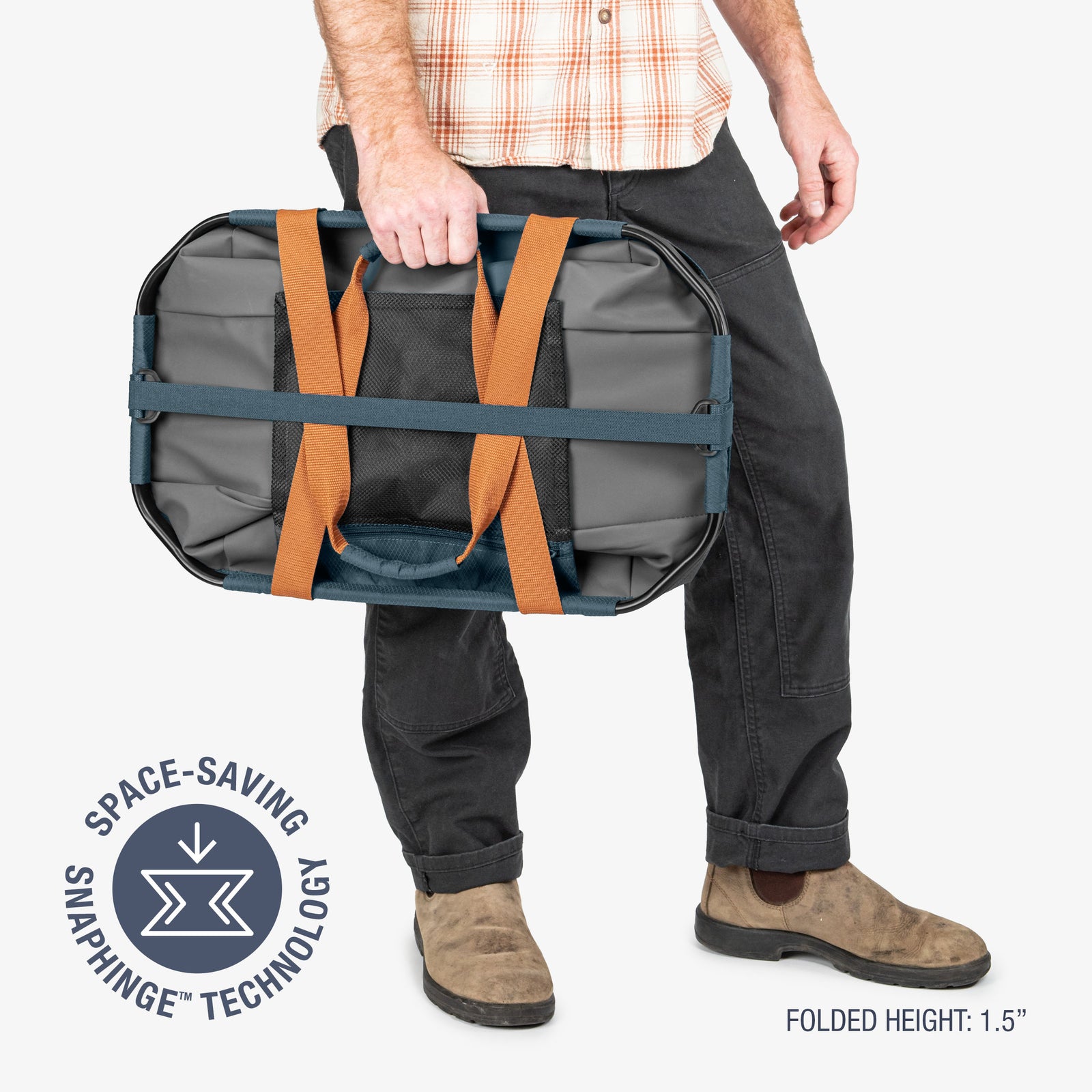 Person holding a gray duffel bag with orange straps, featuring space-saving snap hinge technology on a white background.