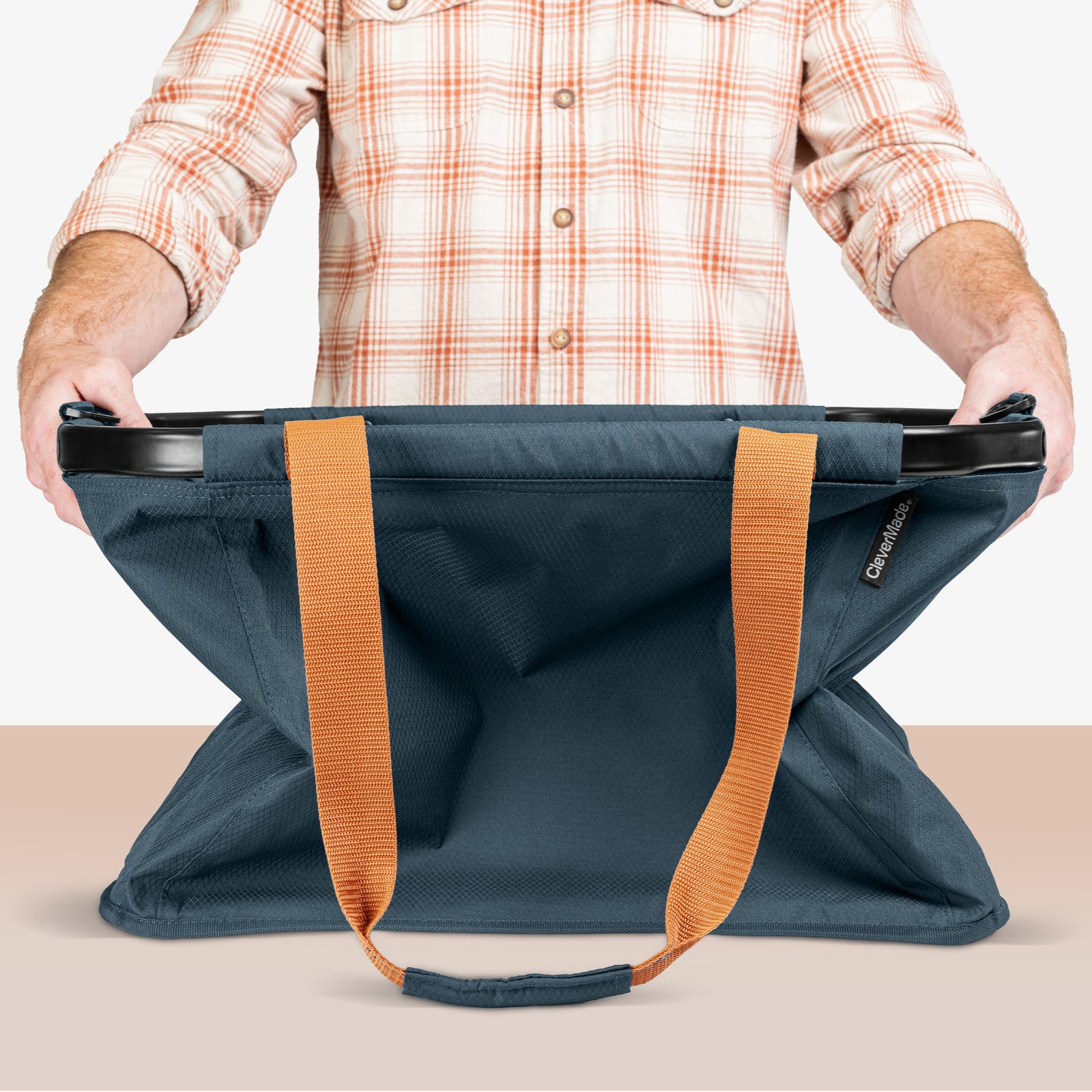 Person holding a blue bag with orange straps on a beige background