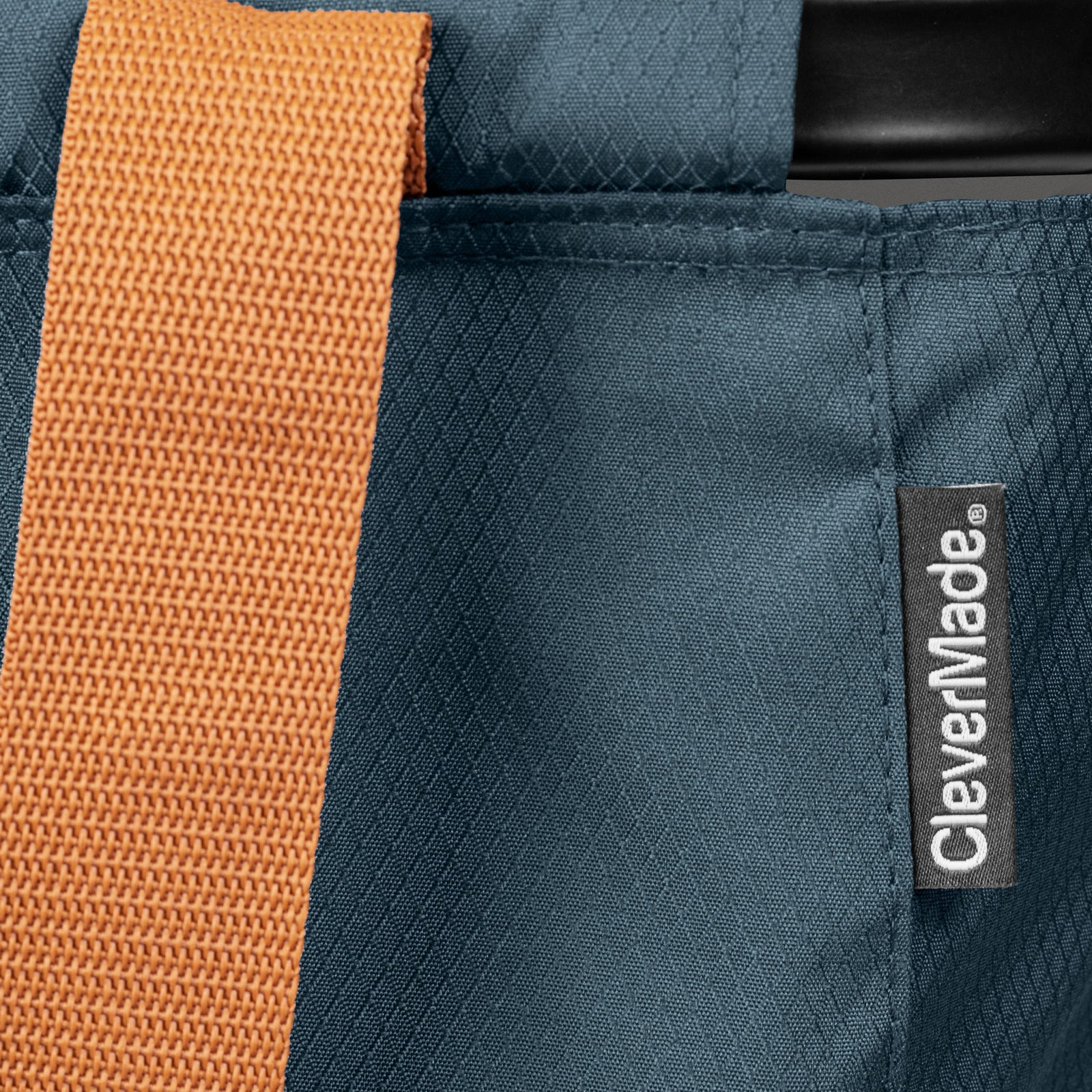 Close-up of a blue bag with an orange strap and CleverMade label.