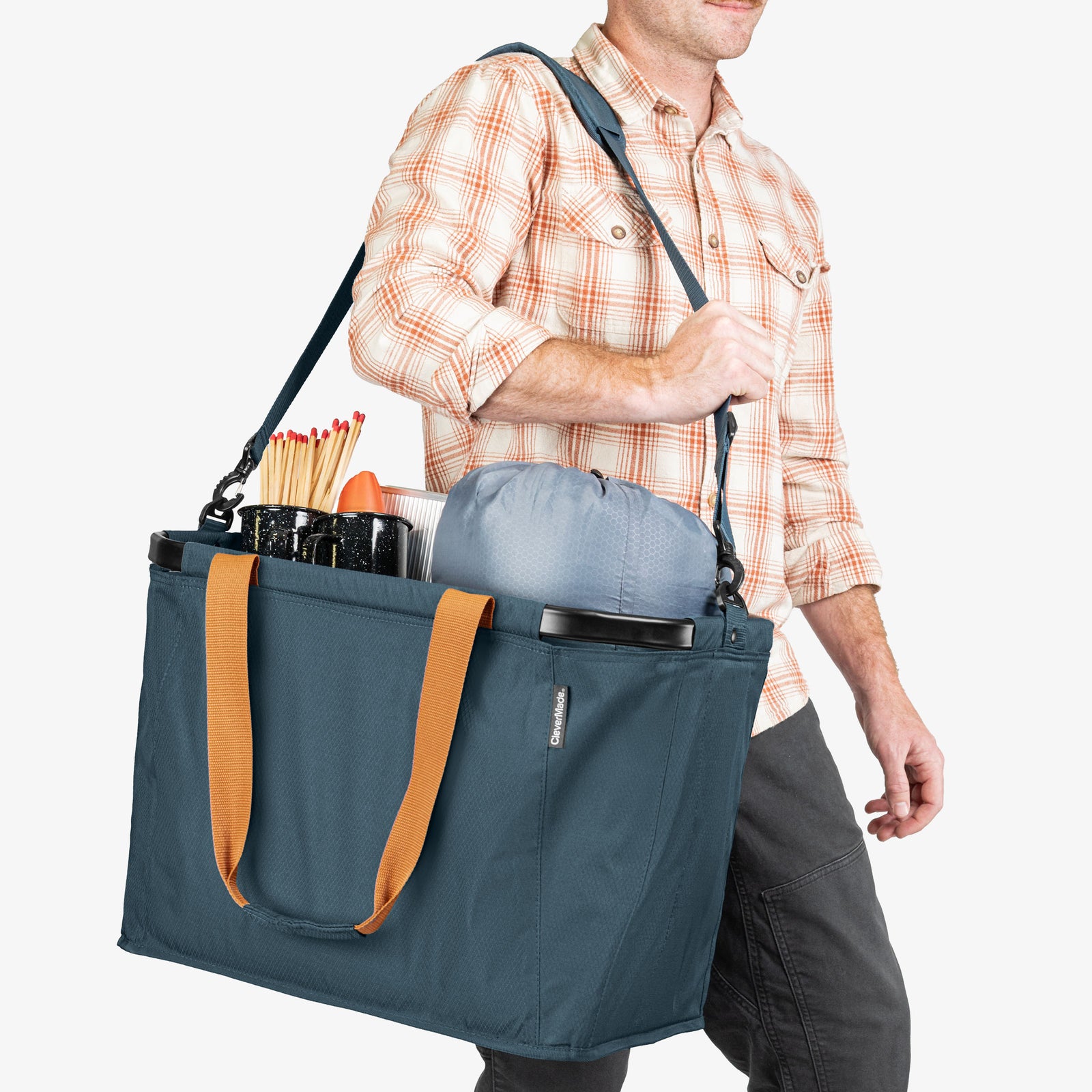 Person carrying a blue tote bag with orange handles on a white background
