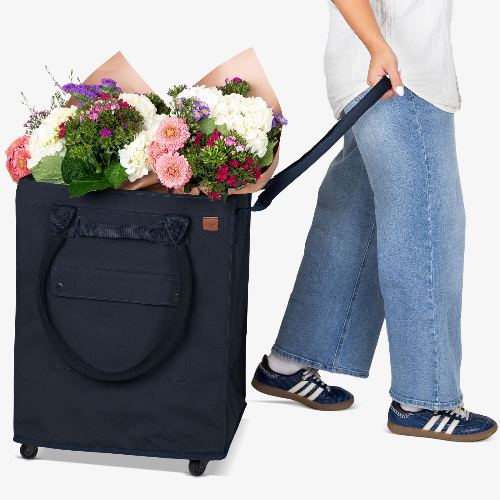 Person holding a navy blue rolling bag filled with flowers, with another person holding the handle.