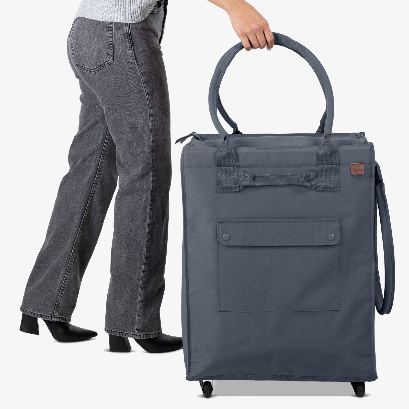 Person holding a large gray rolling tote bag on a white background