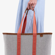 Person holding a tote bag with orange straps against a white background