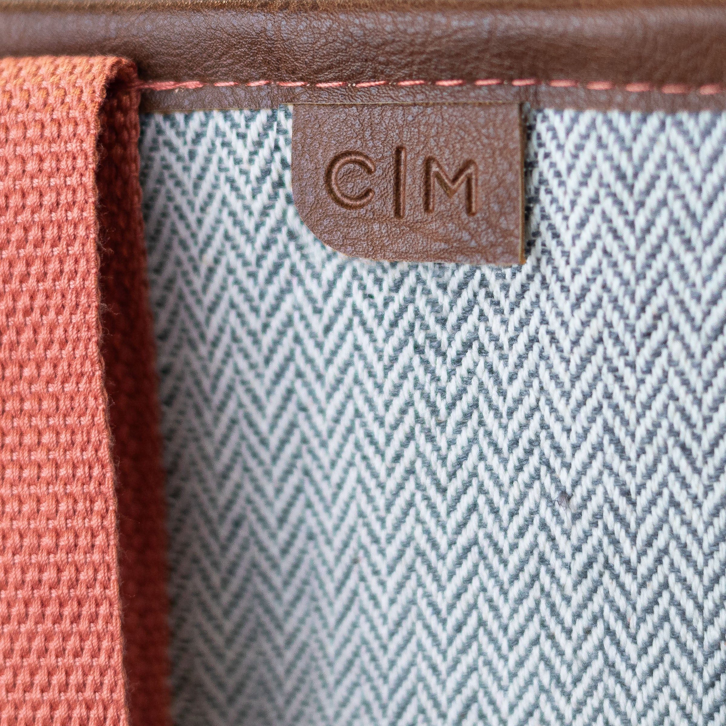 Close-up of a textured fabric surface with a brown leather tag featuring 'C|M'.