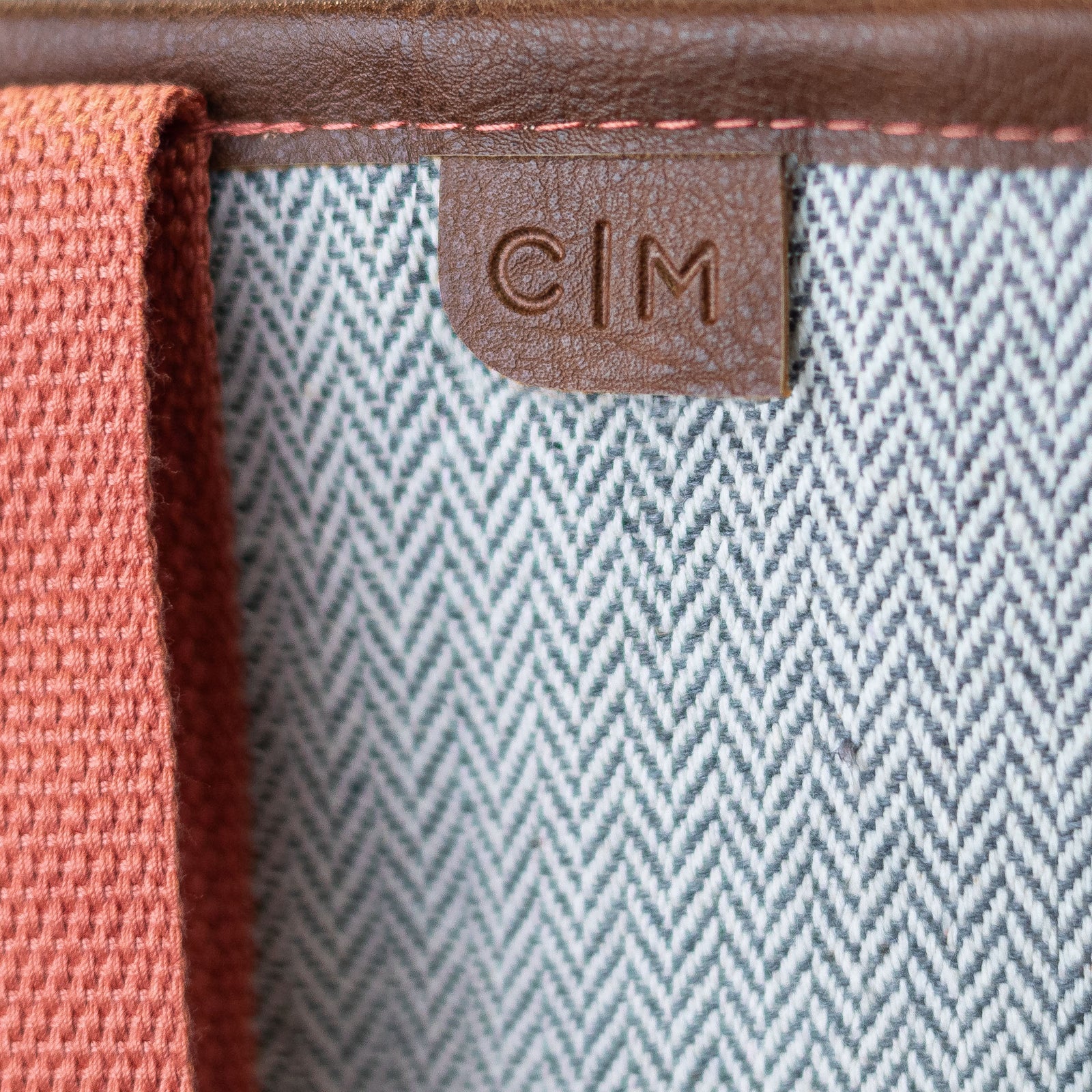 Close-up of a textured fabric surface with a brown leather tag featuring 'C|M'.