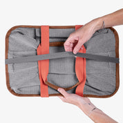 Person holding a gray tote bag with orange straps on a white background