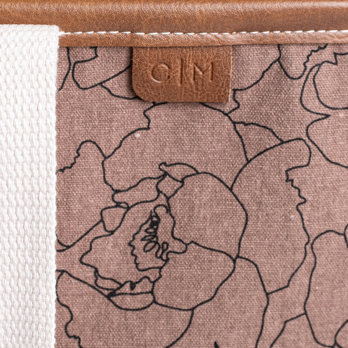Floral patterned tote bag with a brown leather tag displaying C|M