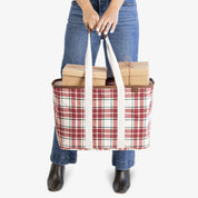 Person holding a plaid tote bag with boxes inside on a white background
