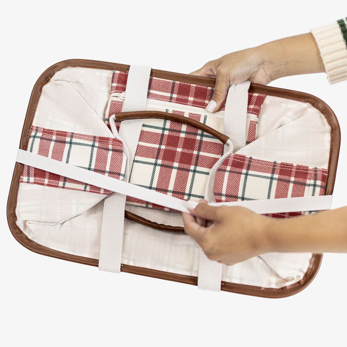 Folded plaid tote bag with brown border held by a person on a white background