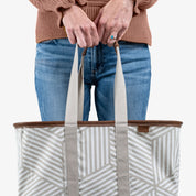 Person holding a striped tote bag with a plain background