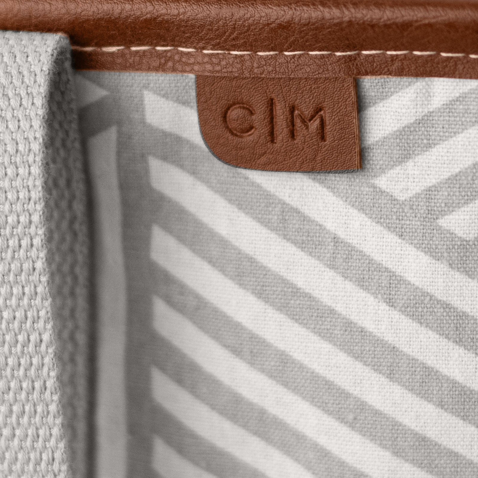Close-up of a tote bag with a brown leather label featuring 'C|M'