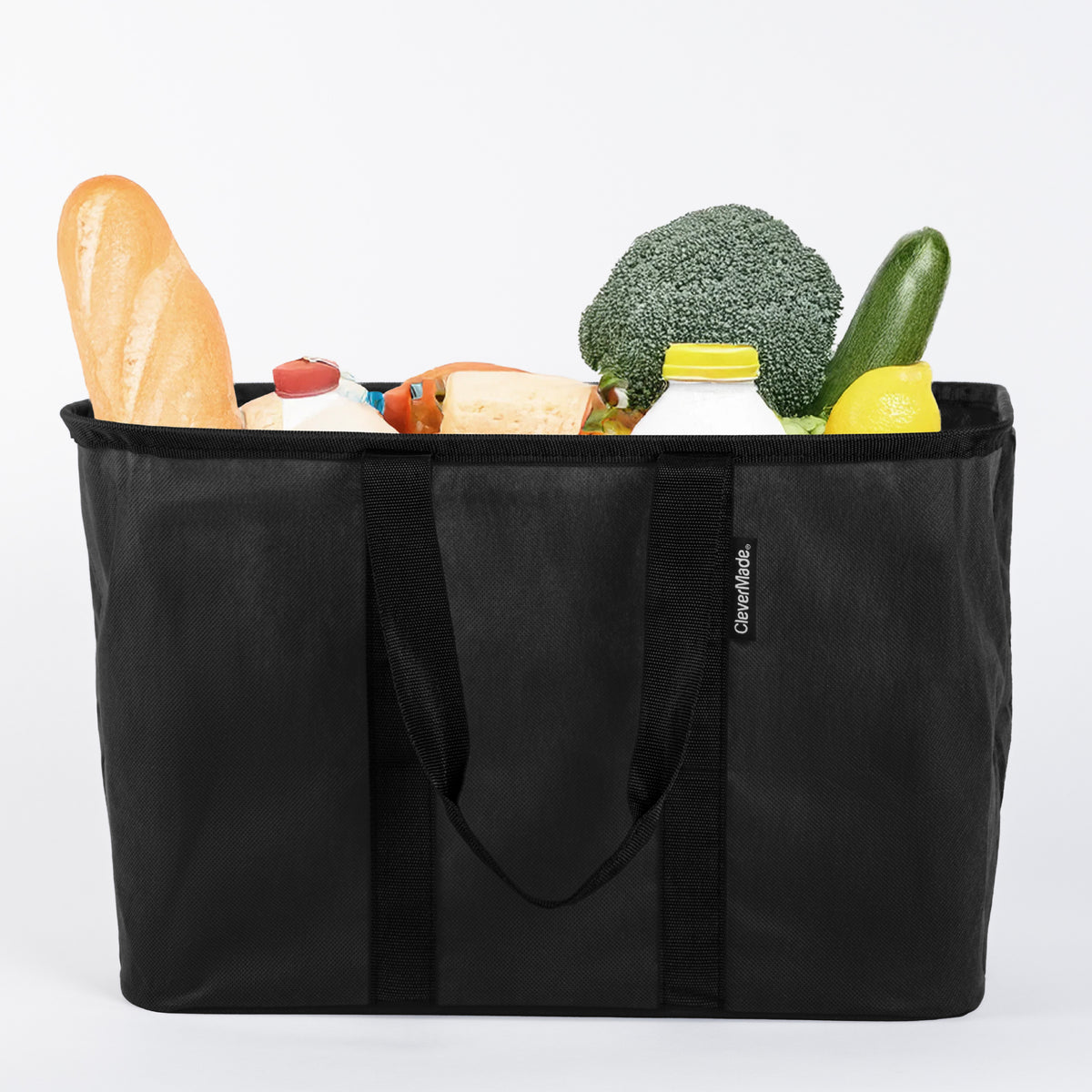 Black reusable shopping bag filled with groceries on a white background