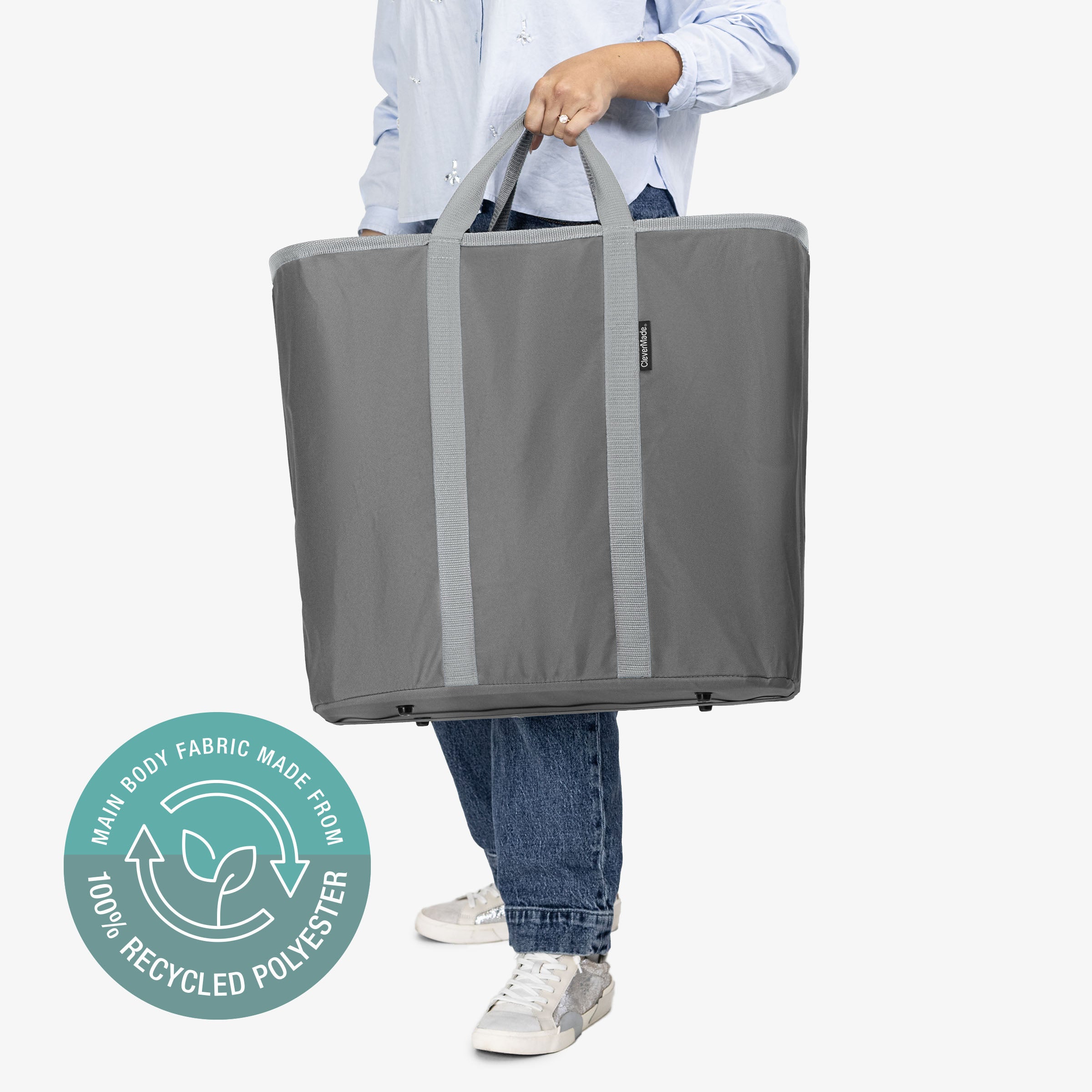 Person holding a large gray tote bag with a recycling logo on a white background