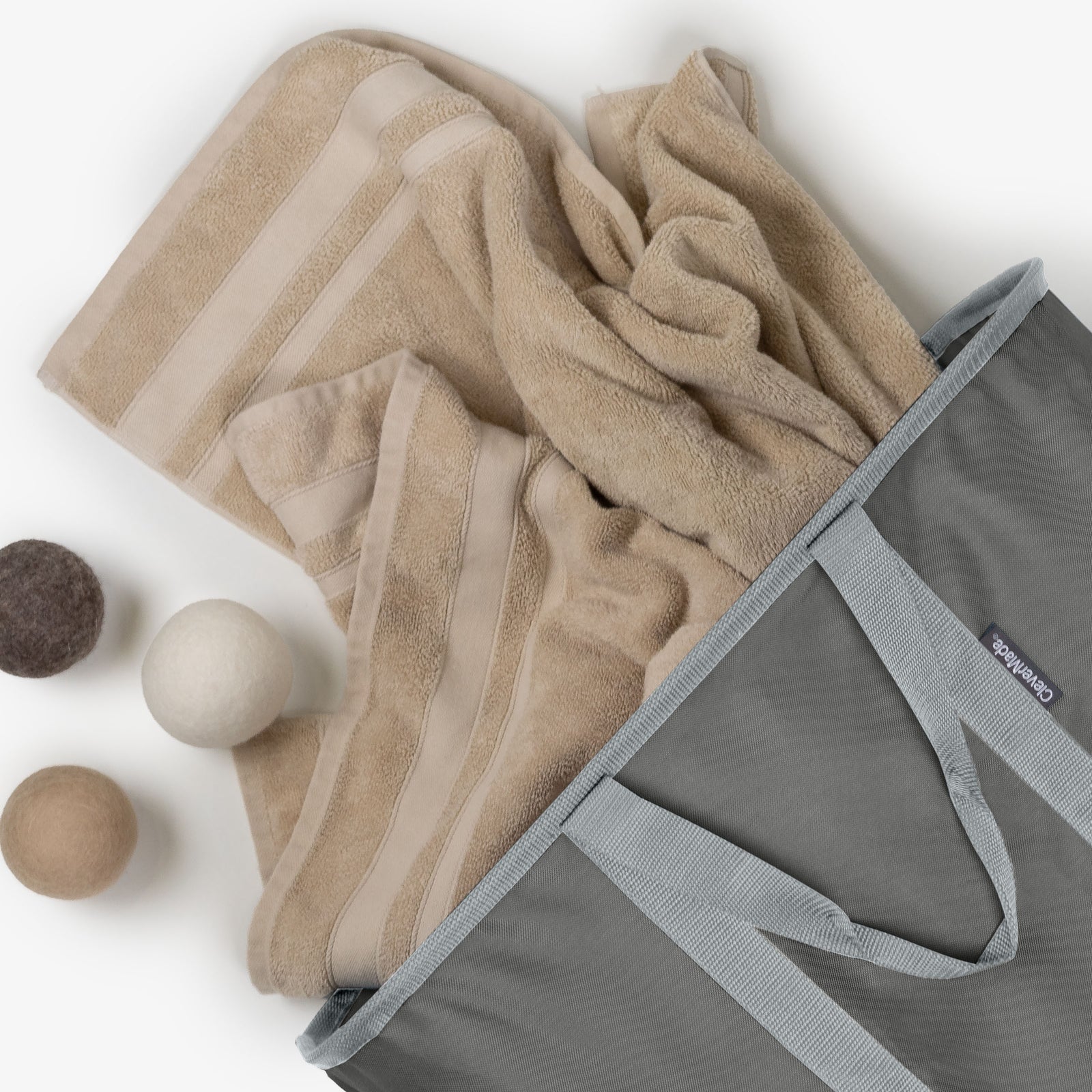 Beige towels in a gray laundry caddy with wooden balls on a white background