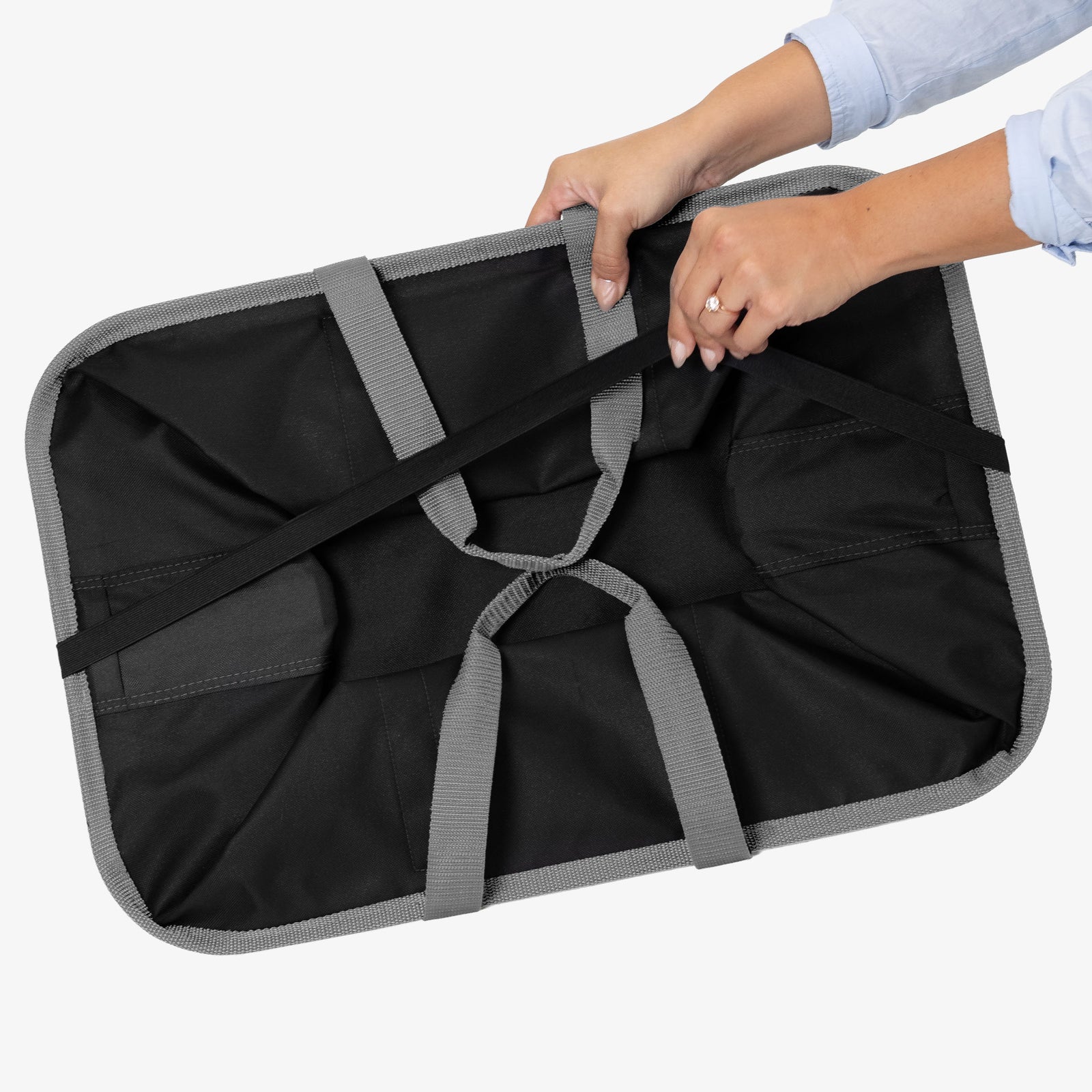 Black and gray laundry caddy with hands holding it on a white background