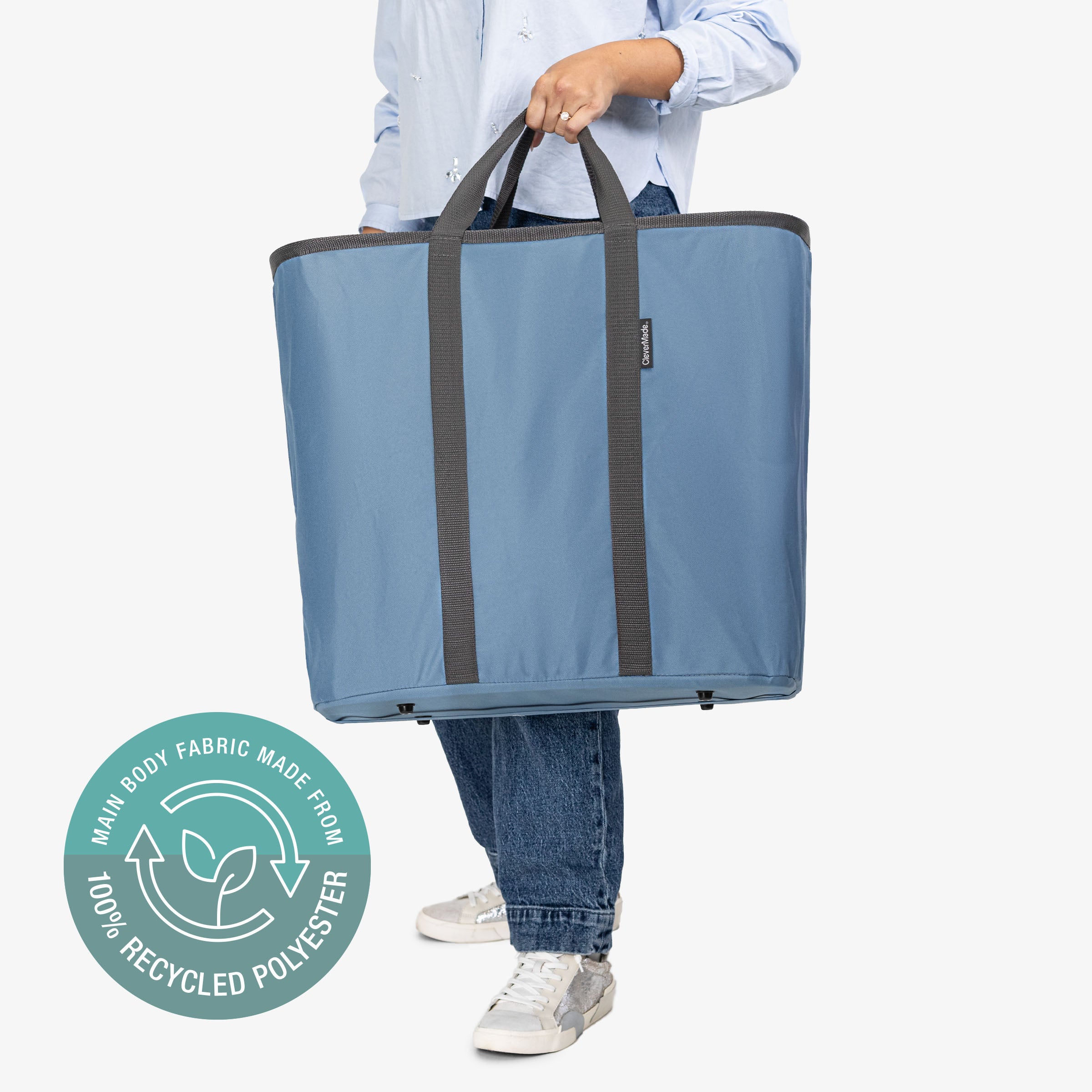 Person holding a blue tote bag with a recycling logo on a white background