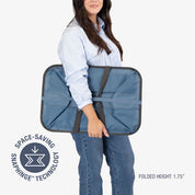 Person holding a blue folding laundry caddy with space-saving snapping technology logo.