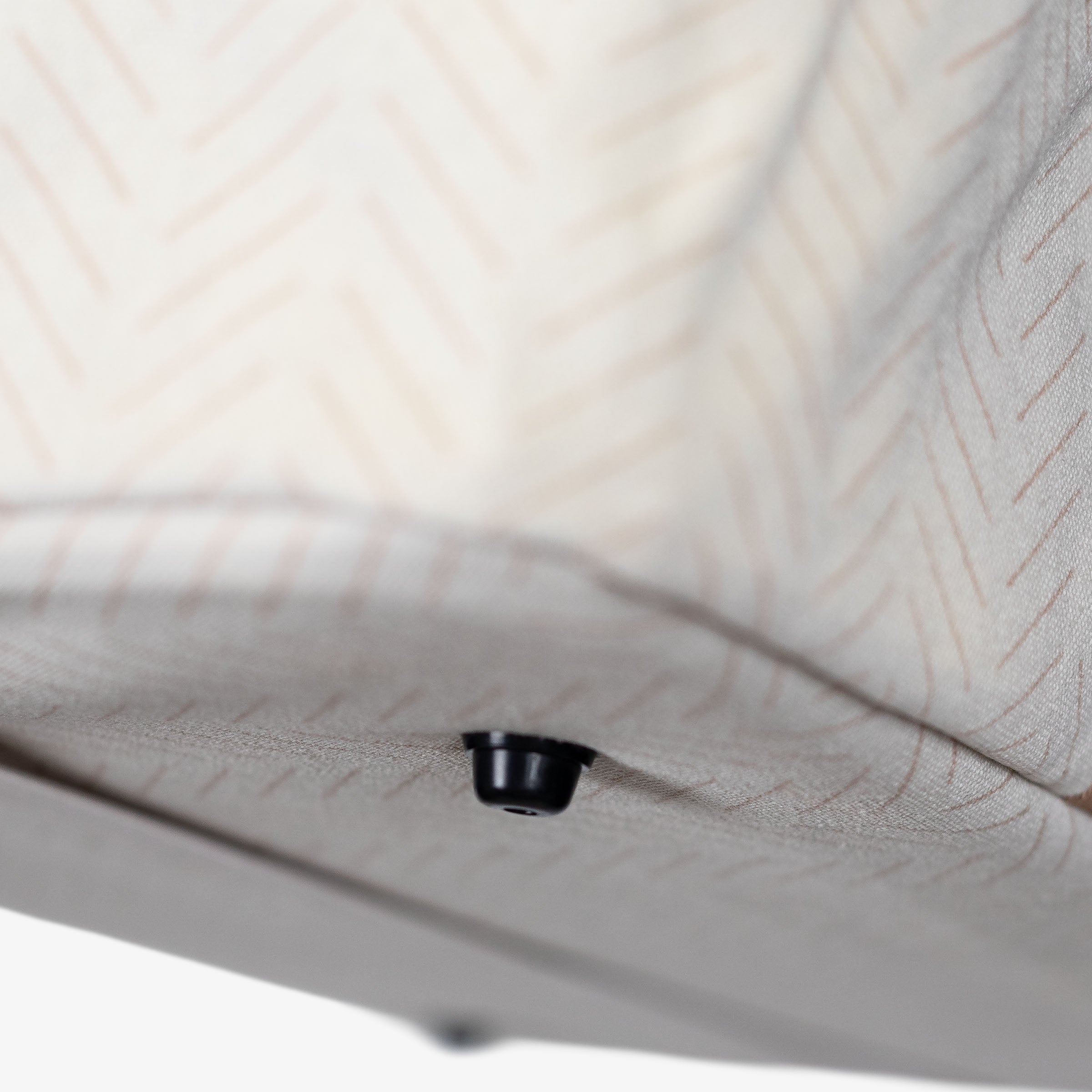 Close-up of a black button foot of a textured beige laundry tote LUXE bag