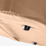 Close-up of a beige laundry tote LUXE bag with a black button foot on a white background