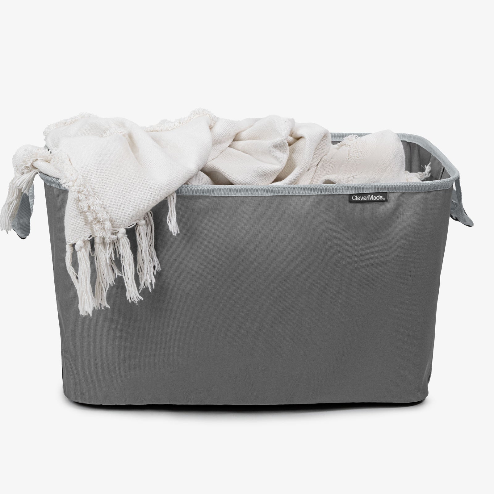 A white garment into a gray CleverMade laundry basket.