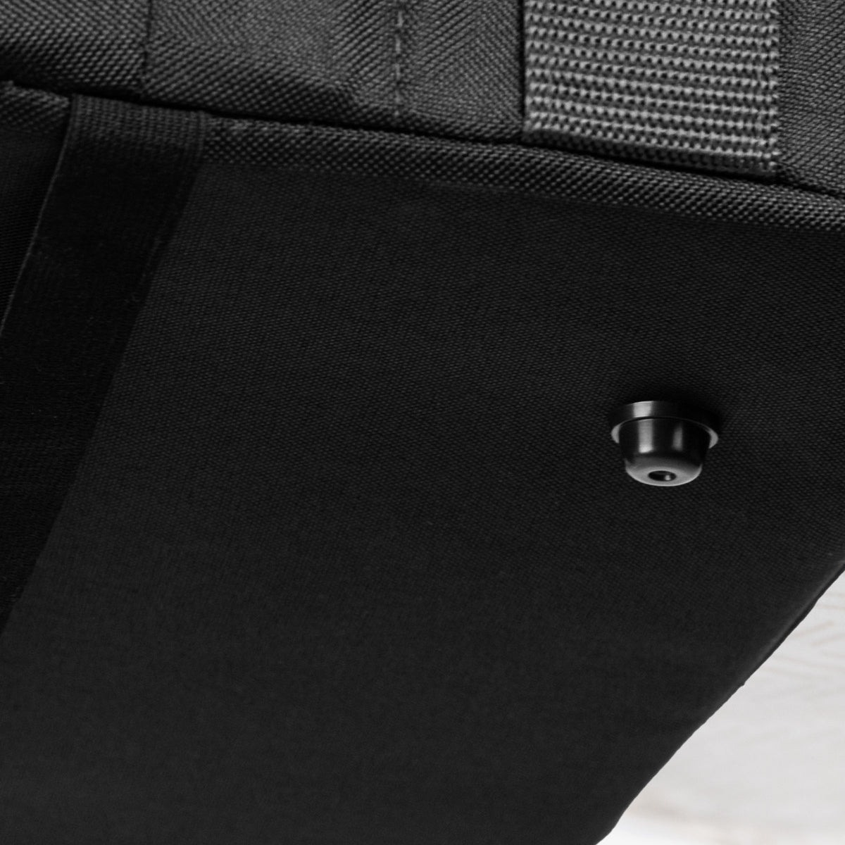 Close-up of a black collapsible laundry basket with a button on a white background