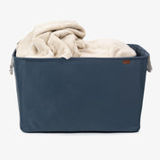 Blue collapsible laundry basket
 with beige blanket on a white background