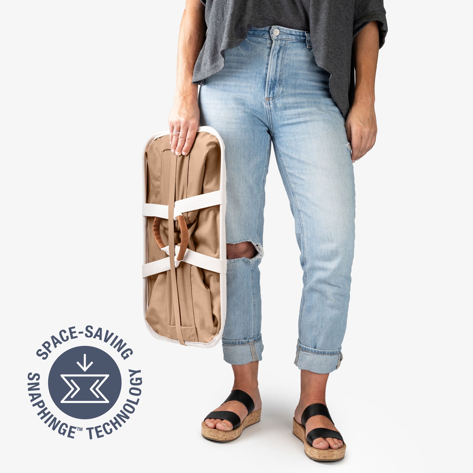 Person holding a beige laundry caddy LUXE with 'Space-Saving Snaphinge Technology' logo on a white background