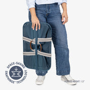 Person holding a blue laundry tote bag with space-saving snap hinge technology on a white background