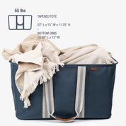 Navy tapered tote with a beige blanket draped over it on a white background