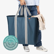 Person holding a large blue tote bag with recycled polyester label
