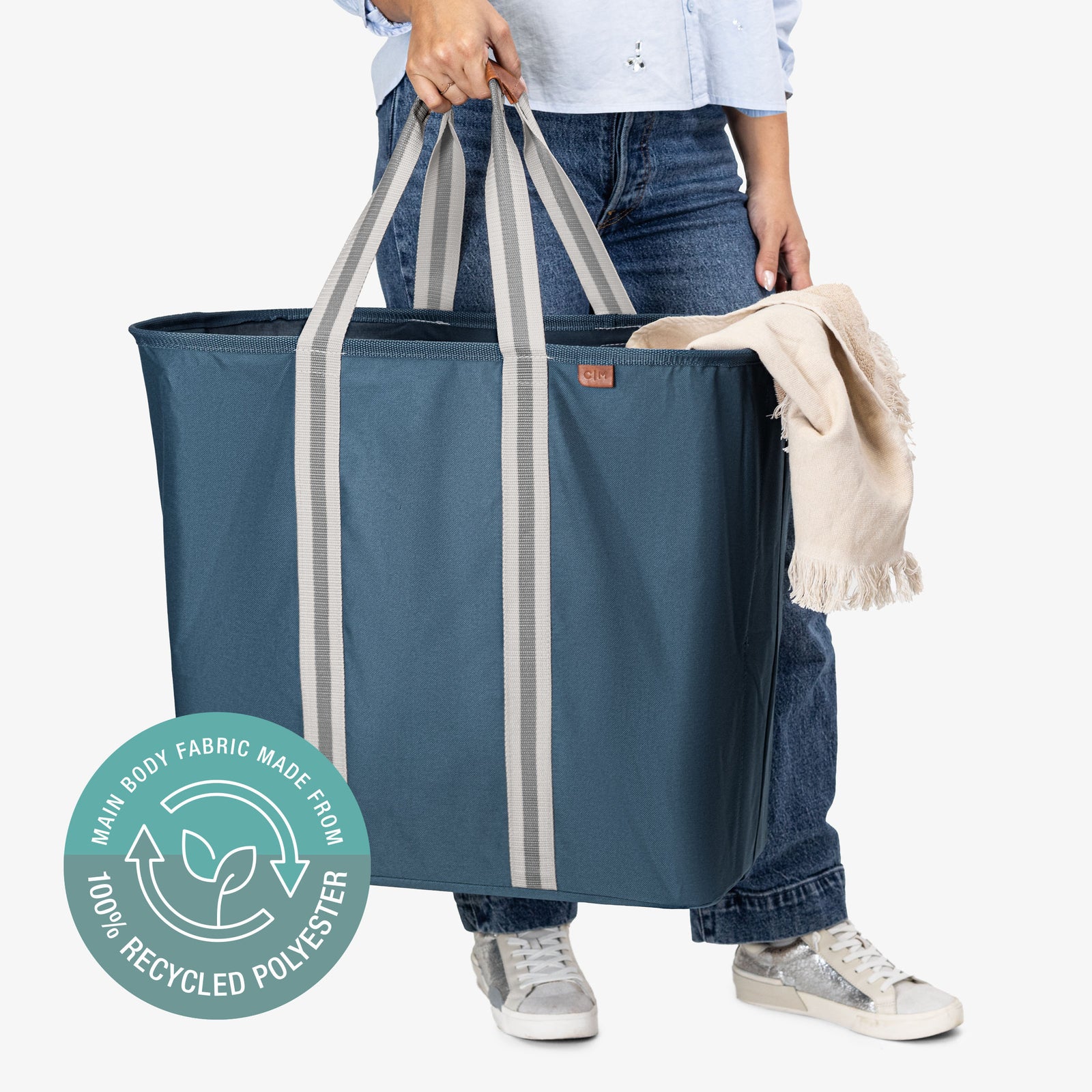 Person holding a large blue tote bag with recycled polyester label