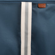 Close-up of a blue bag with a white strap and a brand logo.