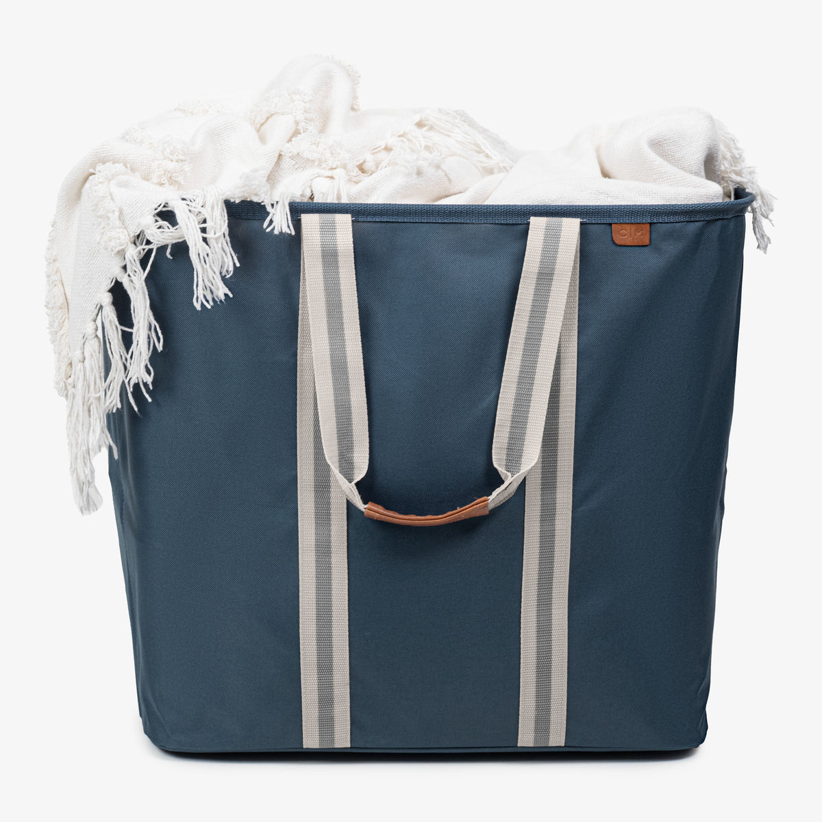 Blue tote bag with white stripes and a white blanket inside on a white background