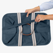 Blue laundry caddy with straps being held by a person on a white background