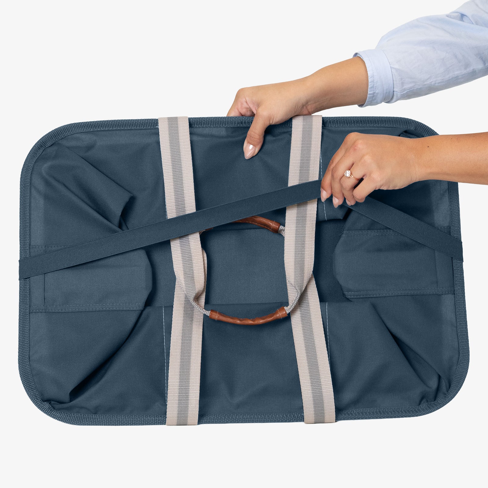Blue laundry caddy with straps being held by a person on a white background