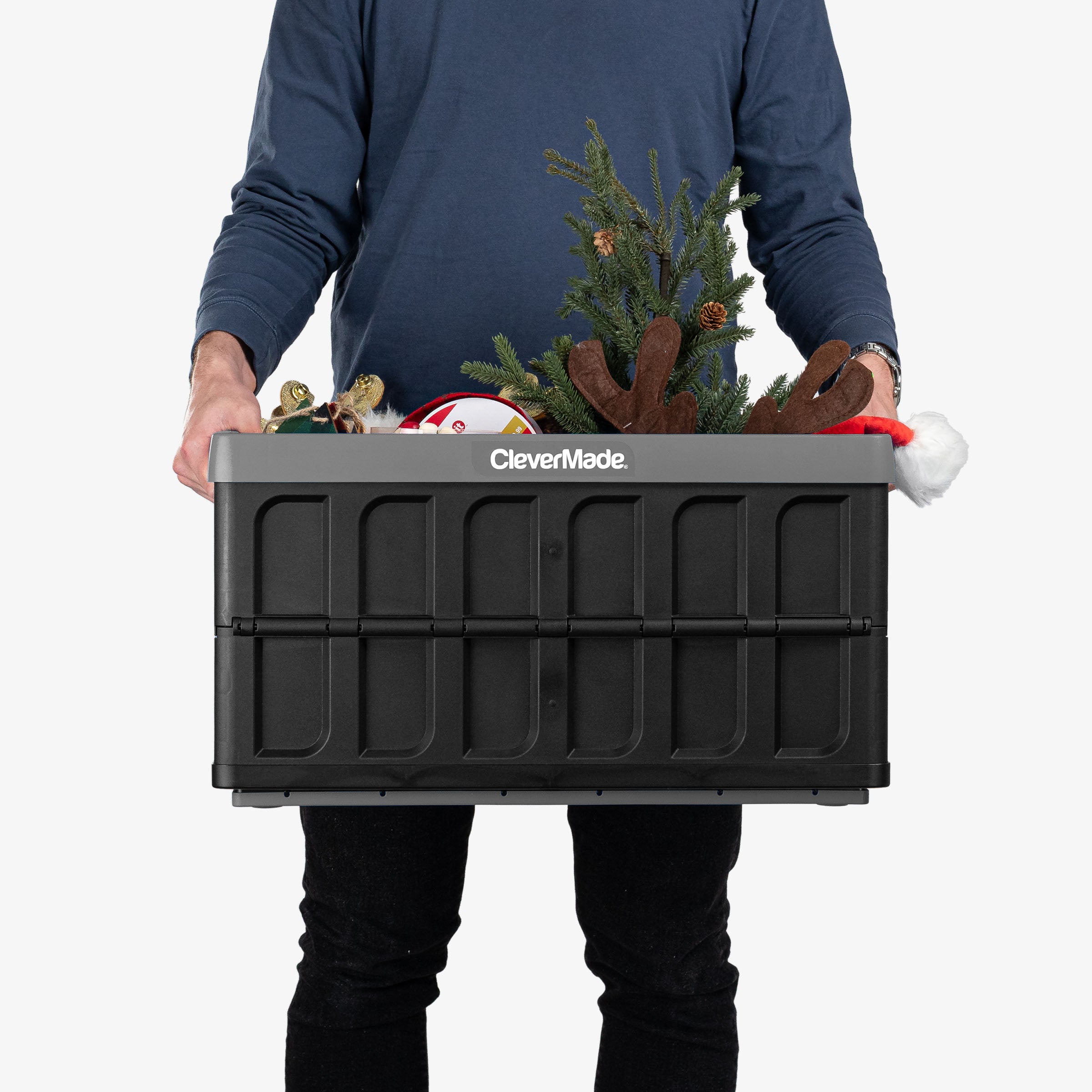 Person holding a CleverMade storage bin with Christmas decorations on a white background